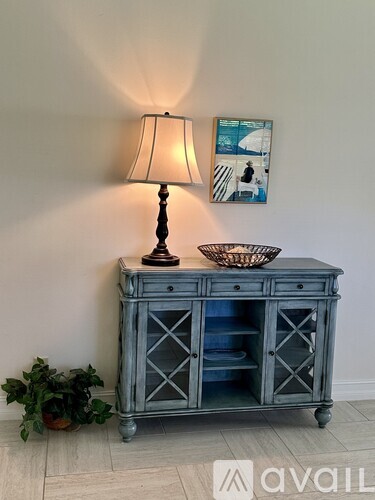 A grey cabinet with a lamp on top and a basket on the side.