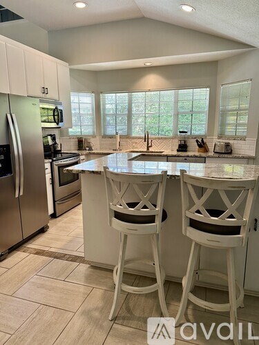 A kitchen with white chairs and a marble countertop.