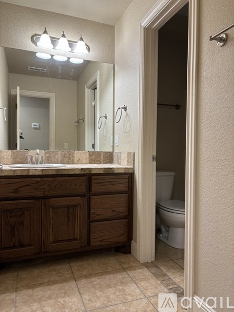 A bathroom with a wooden vanity and a mirror above it.