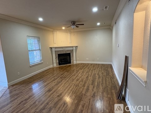 A spacious room with a fireplace and wooden flooring.