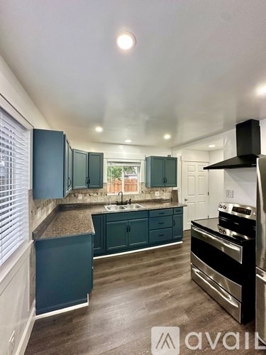 A kitchen with dark teal cabinets and stainless steel appliances.