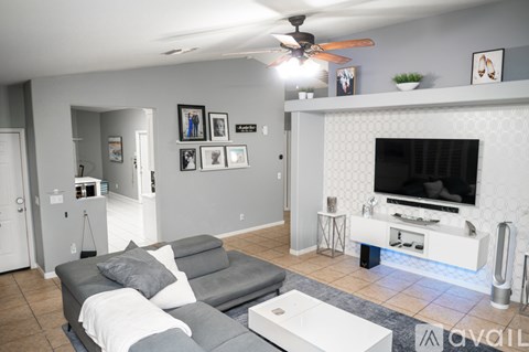A living room with a grey couch and a white fireplace.