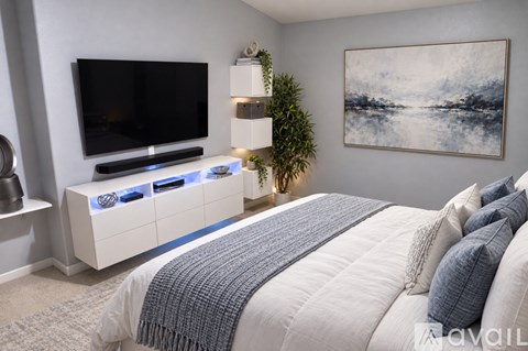 A modern bedroom with a large bed and a television on the wall.