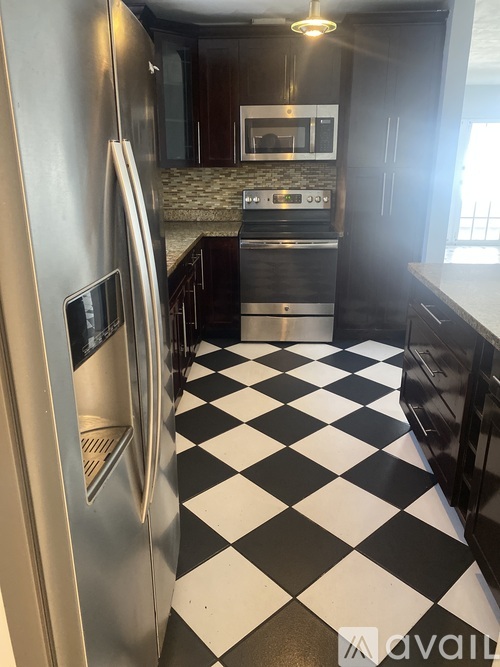 A kitchen with a checkered floor and a stainless steel refrigerator.