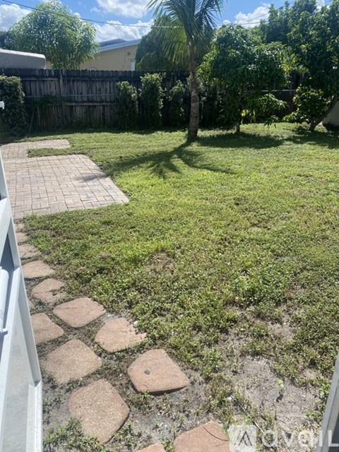 A backyard with a brick pathway and a grassy area.