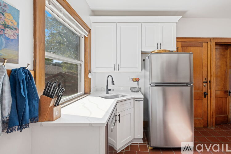 A kitchen with white cabinets and a stainless steel refrigerator.