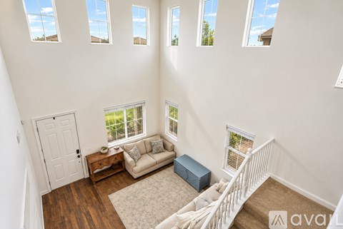 A living room with a couch, a table, and a window with blinds.