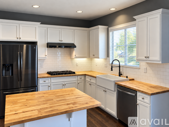 A kitchen with white cabinets and a wooden countertop.