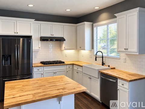 A kitchen with white cabinets and a wooden countertop.