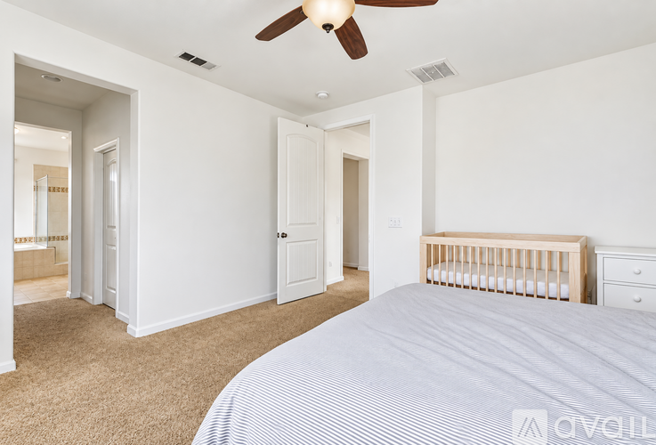A bedroom with a large bed, dresser, and a ceiling fan.
