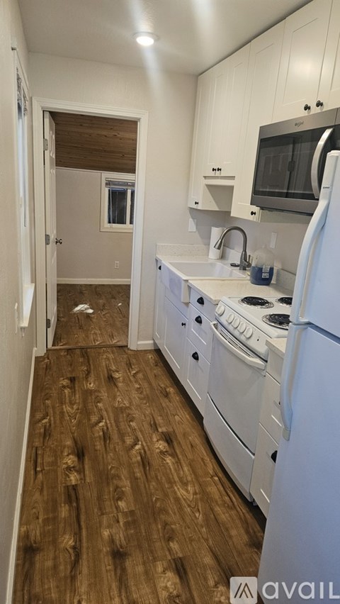A kitchen with white appliances and wood floors.