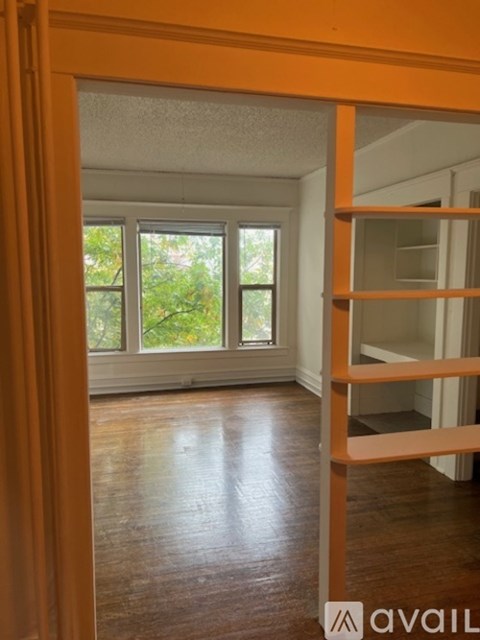 A room with wooden floors and a window with a view of trees.