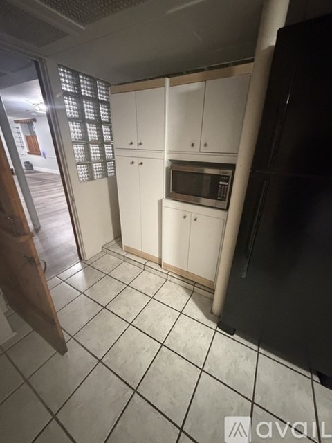 A kitchen with white cabinets and a black refrigerator.