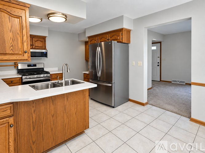 A kitchen with wooden cabinets and a stainless steel refrigerator.