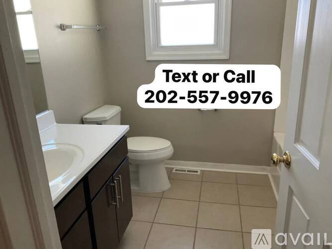 A bathroom with a toilet, sink, and a window.