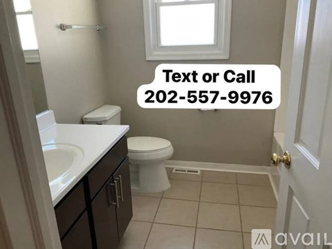 A bathroom with a toilet, sink, and a window.