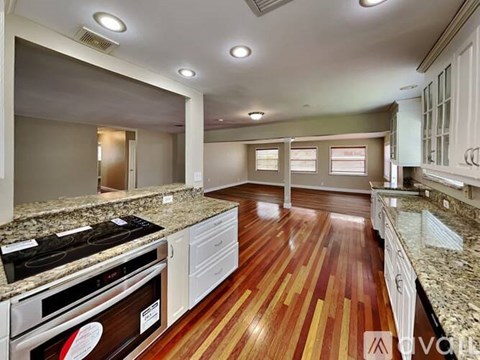 A kitchen with a wood floor and white cabinets.