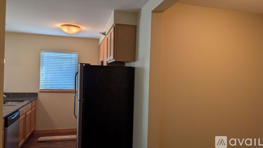 A kitchen with a black refrigerator and wooden cabinets.