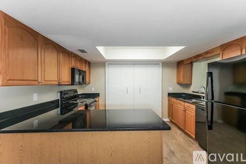 A kitchen with wooden cabinets and black countertops.