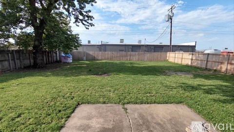 A backyard with a concrete slab in the middle of a grassy area.