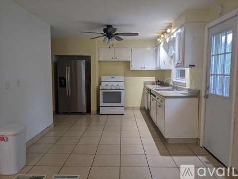 A kitchen with white cabinets and a fan on the ceiling.