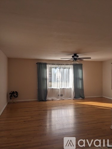 A room with wooden flooring and a ceiling fan.
