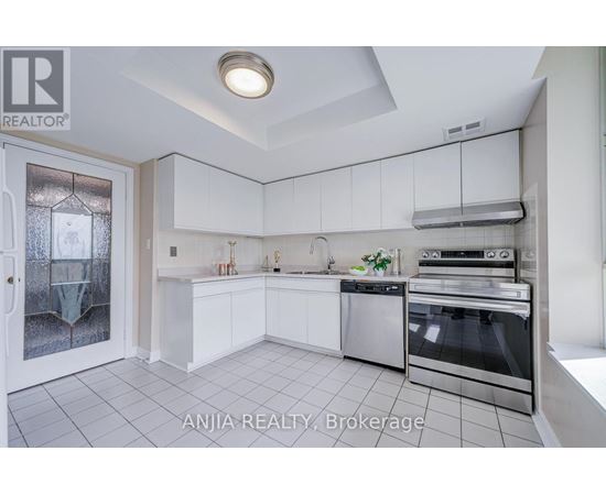 A well-lit kitchen with white cabinets and stainless steel appliances.