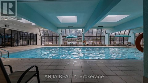 A large indoor swimming pool with a glass wall on one side.