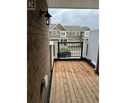 A wooden deck with a black railing and a brick wall.