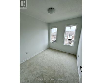 A room with a carpeted floor and two windows.