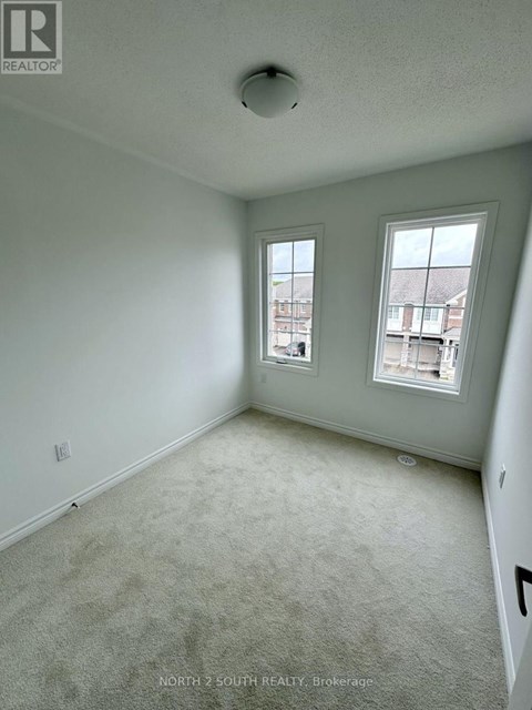A room with a carpeted floor and two windows.