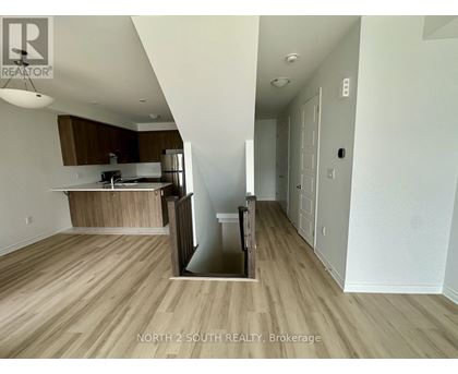 A kitchen with a refrigerator, sink, and cabinets is shown in a real estate listing.
