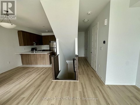 A kitchen with a refrigerator, sink, and cabinets is shown in a real estate listing.