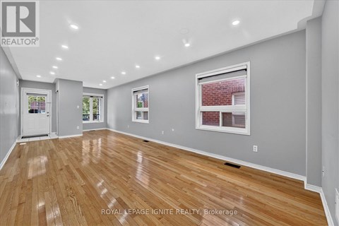 A spacious room with wooden flooring and white walls.