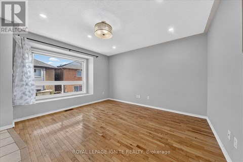A room with wooden flooring and a window showing a view of a building outside.