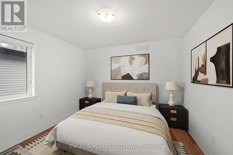 A bedroom with a bed, two nightstands, and a painting on the wall.