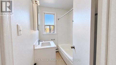A white bathroom with a tub, sink, and mirror.