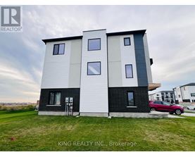 A modern two-story house with a white and black exterior is for sale.
