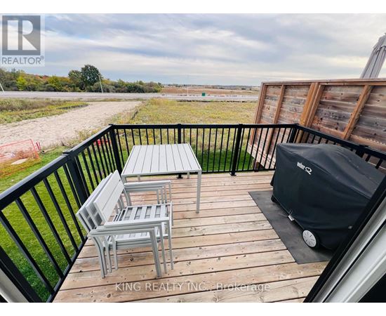 A balcony with a table and chairs overlooking a field.