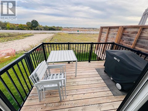 A balcony with a table and chairs overlooking a field.