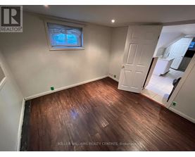A room with wooden flooring and a window with a view of trees.