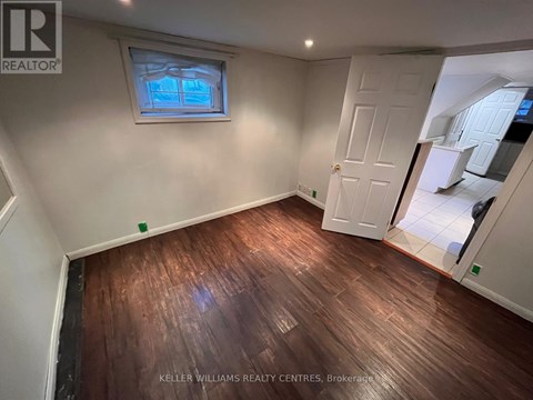 A room with wooden flooring and a window with a view of trees.