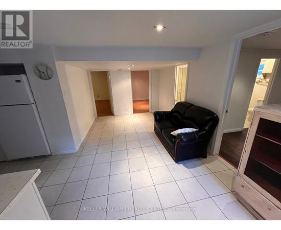 A living room with a black couch and a white refrigerator.