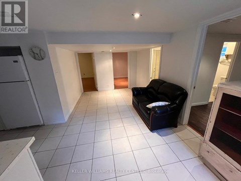 A living room with a black couch and a white refrigerator.