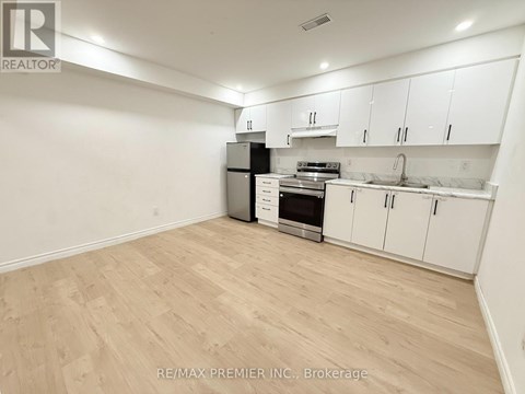 A kitchen with white cabinets and a wooden floor.