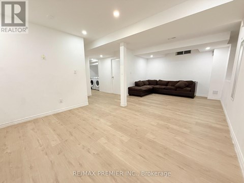 A spacious living room with a brown couch and wooden flooring.