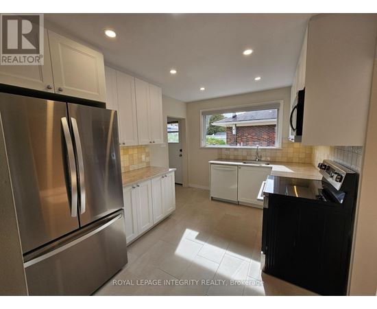 A kitchen with a stainless steel refrigerator and white cabinets.