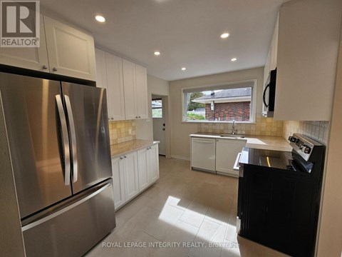 A kitchen with a stainless steel refrigerator and white cabinets.