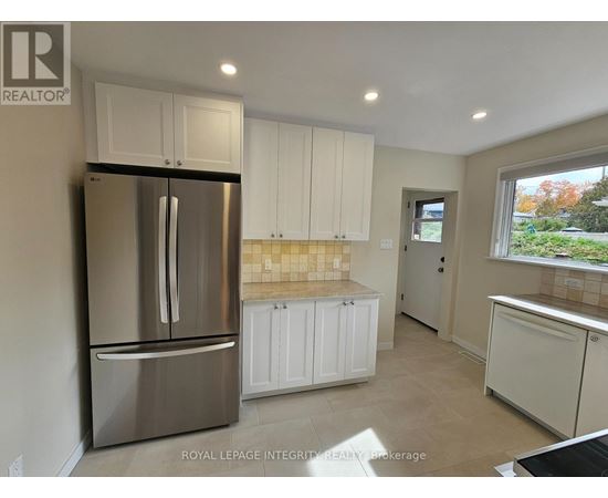 A kitchen with white cabinets and a stainless steel refrigerator.