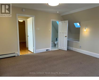 A room with a carpeted floor and a doorway leading to another room.